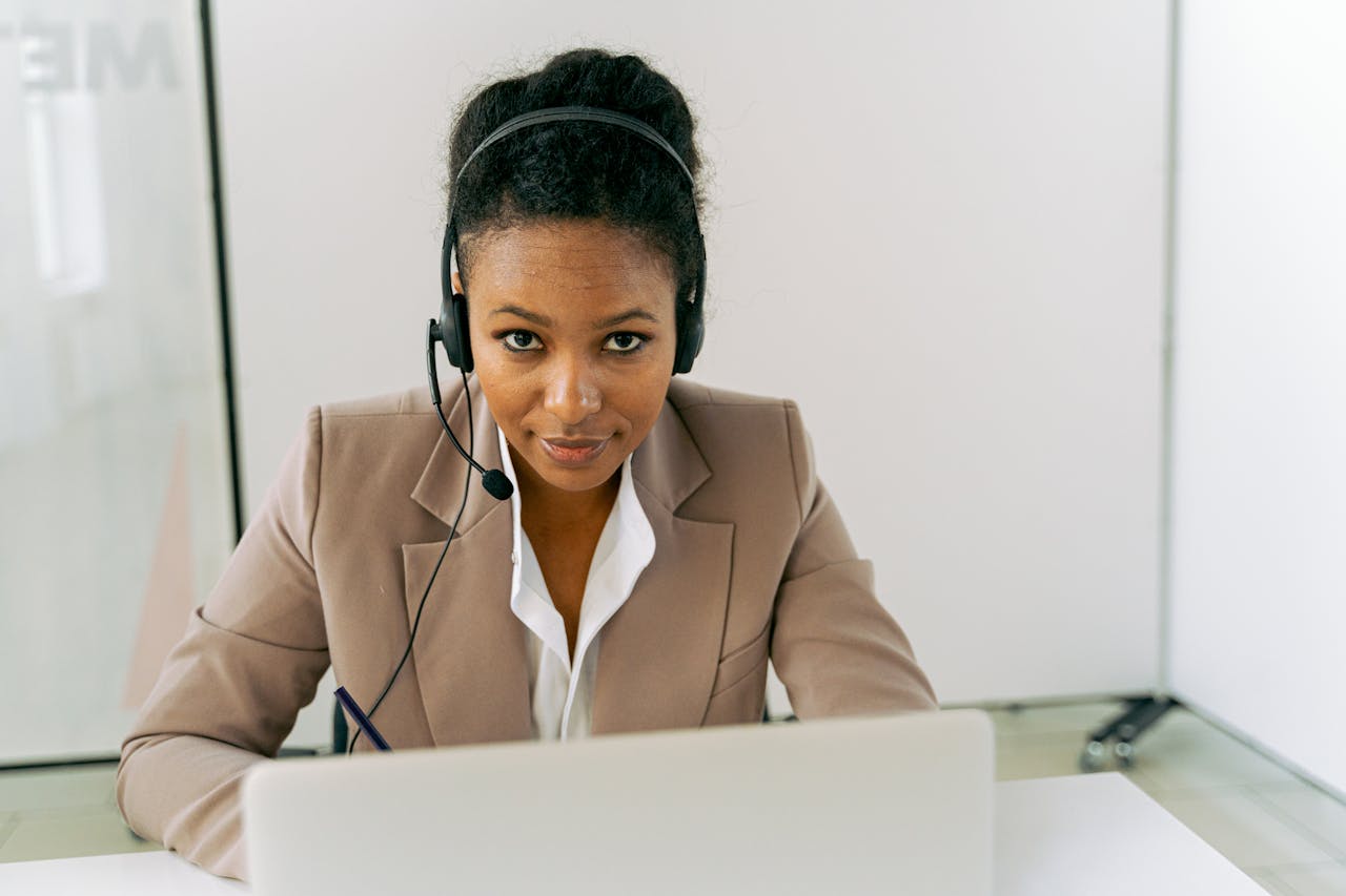 embark Confident woman in a call center setting, wearing a headset and suit, ready to assist.