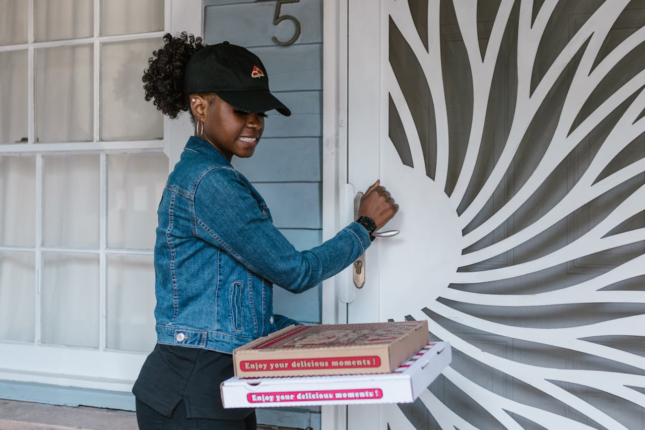 why-choose-us-01 Female delivery driver holding pizza boxes at doorstep ready for delivery.