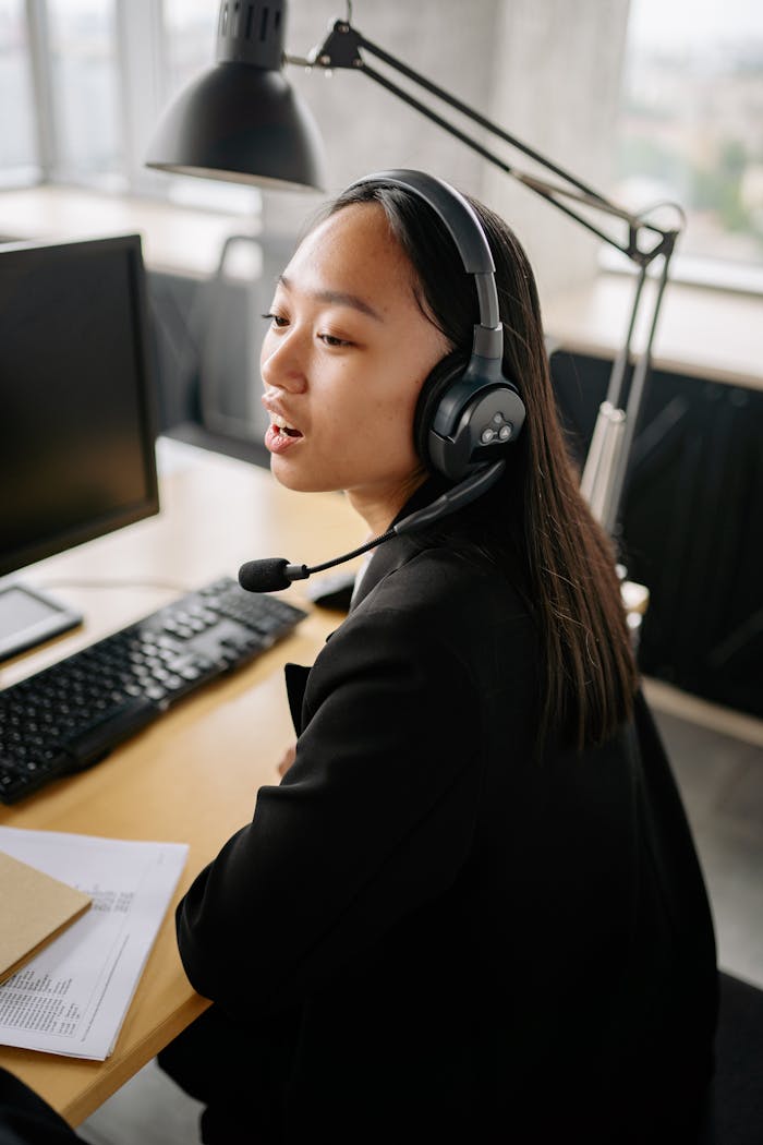 services-02 Asian woman using headset for customer support in a modern office.